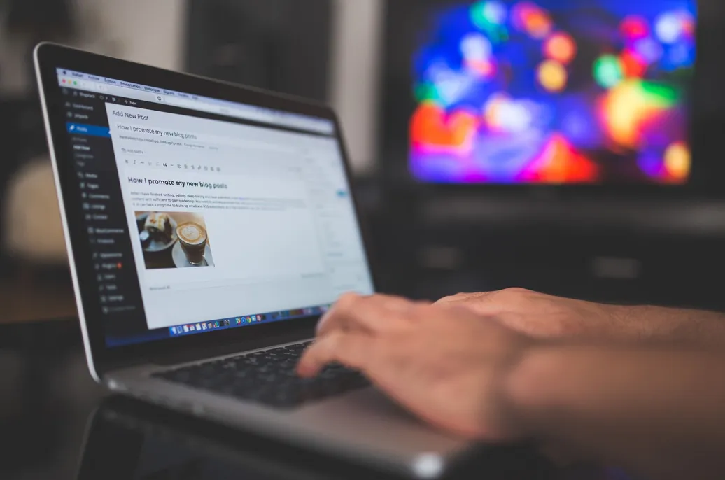 Hands typing a blog post in the WordPress editor on a laptop